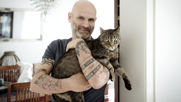 Tattooed man carrying his cat