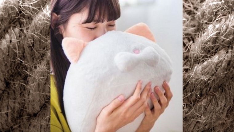 A woman presses her face against a cat head-shaped pillow.