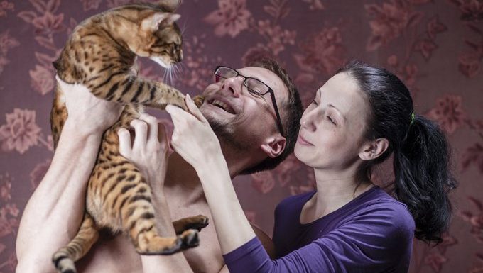 couple holding a cat up high
