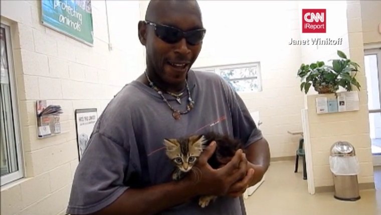 Frazier holds the kitten in his hands at the shelter
