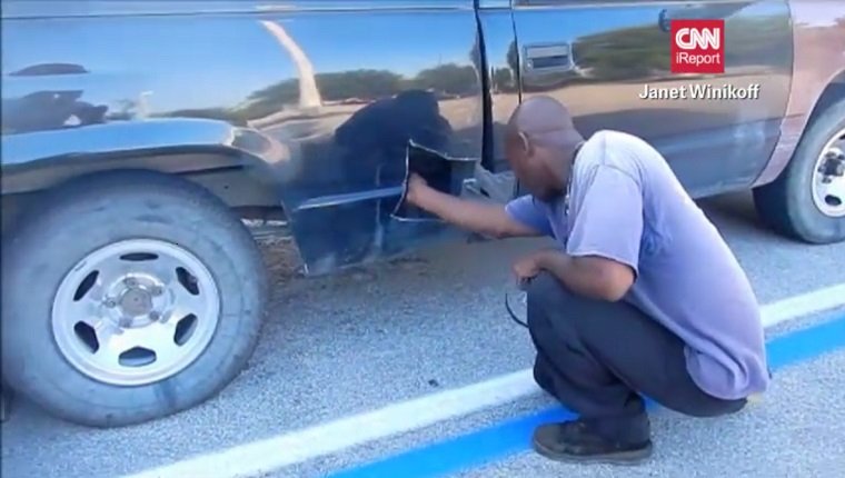 Frazier sticks his arm in a hole in his truck