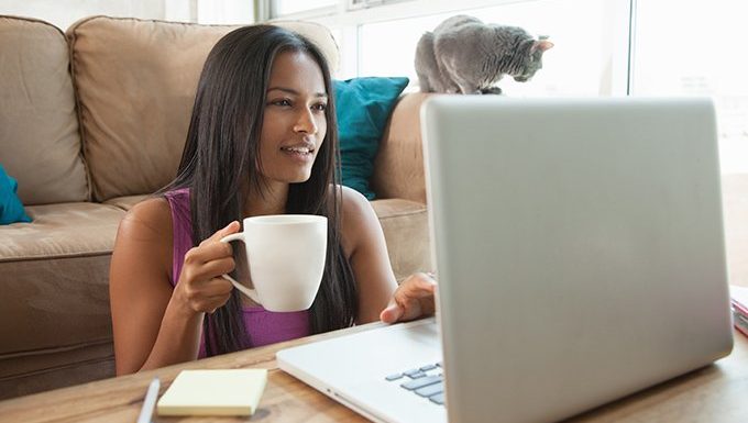woman on laptop with cat in background