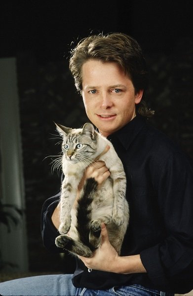BEVERLY HILLS, CA - 1988: Actor Michael J. Fox poses with his cat during a 1988 Beverly Hills, California, photo portrait session. Fox, a three-time Emmy Award winner for his work on TV's "Family Ties," also starred in the "Back to the Future" film trilogy. (Photo by George Rose/Getty Images)