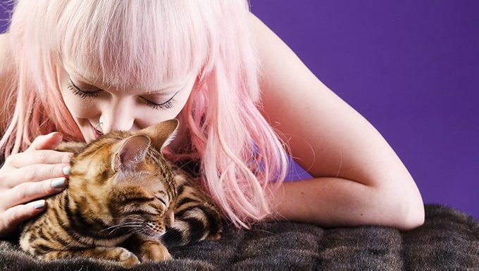 woman with pink hair massaging cat