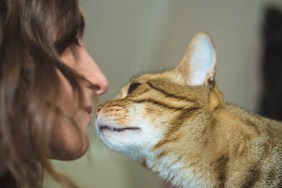 A young woman approaches her face to her cat