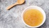 Bowl of chicken broth on table with wooden spoon.