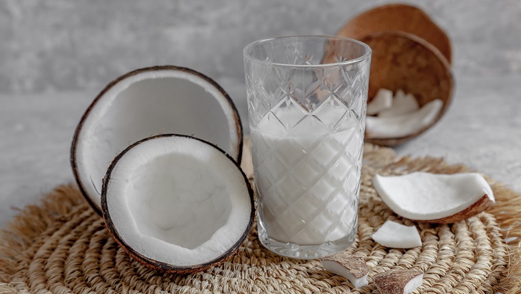 Opened coconuts, glass of homemade coconut milk and coconut chunks