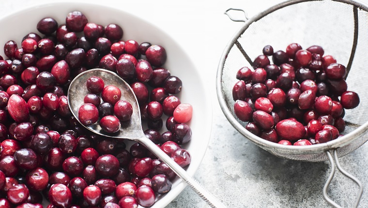 Fresh cranberries in a white bowl with spoon