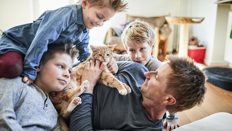 Father and children lying down at home with cat