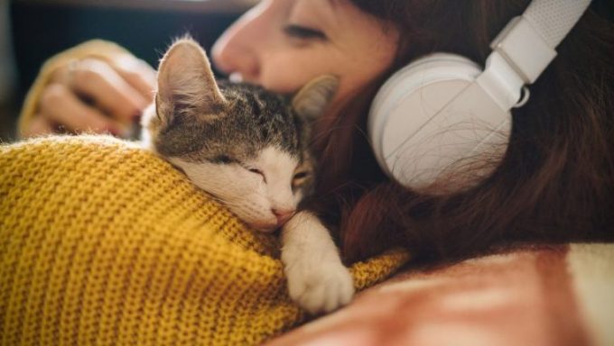 woman wearing headphones cuddling cat best cat names inspired by music