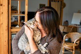 middle-aged woman hugging Tabby cat