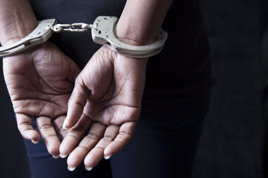 A woman in handcuffs, similar to the one who was arrested for poisoning her neighbors' cats and a pregnant dog with a pesticide.